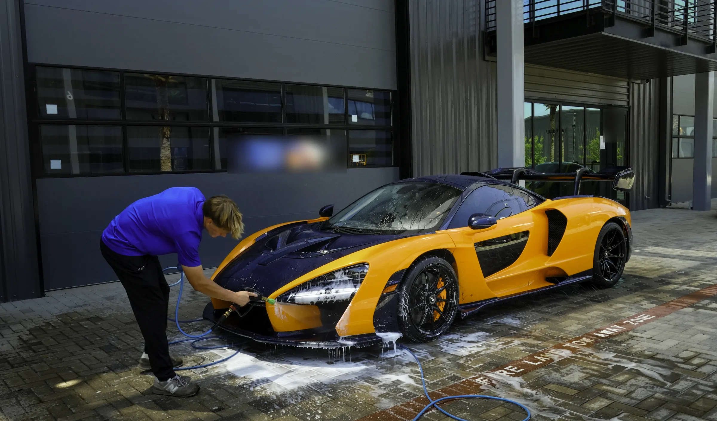 Tegan pressure-washing a McLaren Senna
